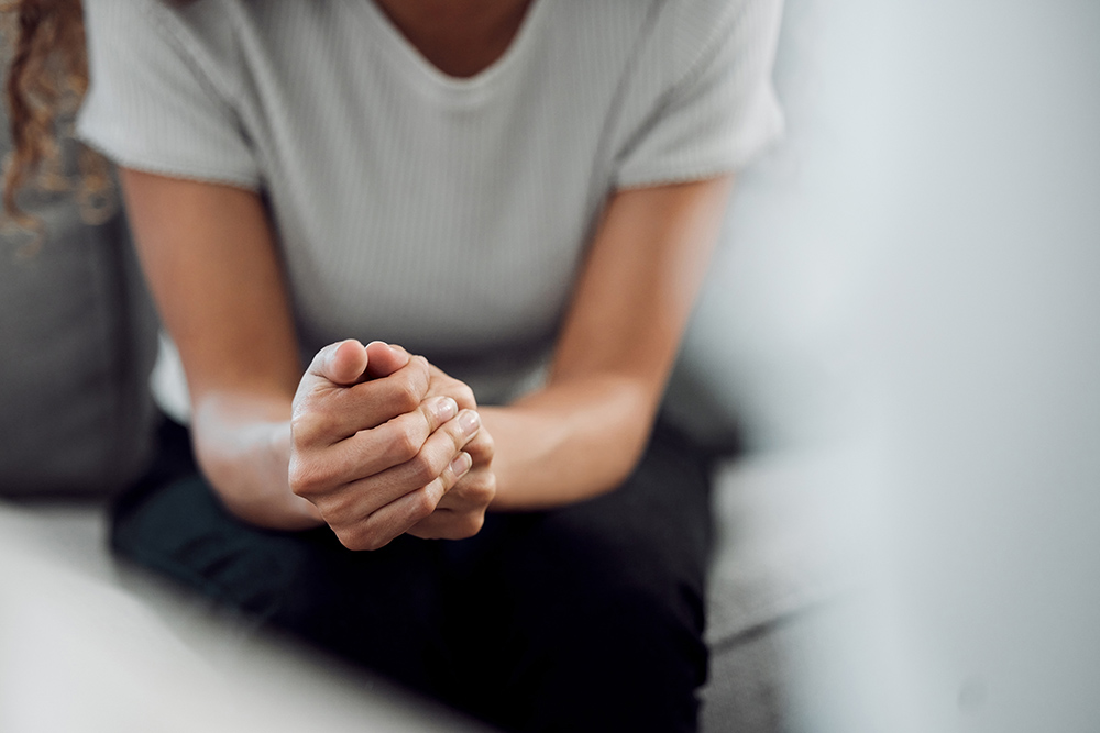 Hands, psychology and mental health with a woman in a therapy session for grief counseling after loss. Anxiety, stress or depression with a female patient feeling nervous in a clinic for support.